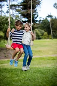 boy-and-girl-sitting-on-a-swing-in-park_107420-82553.webp